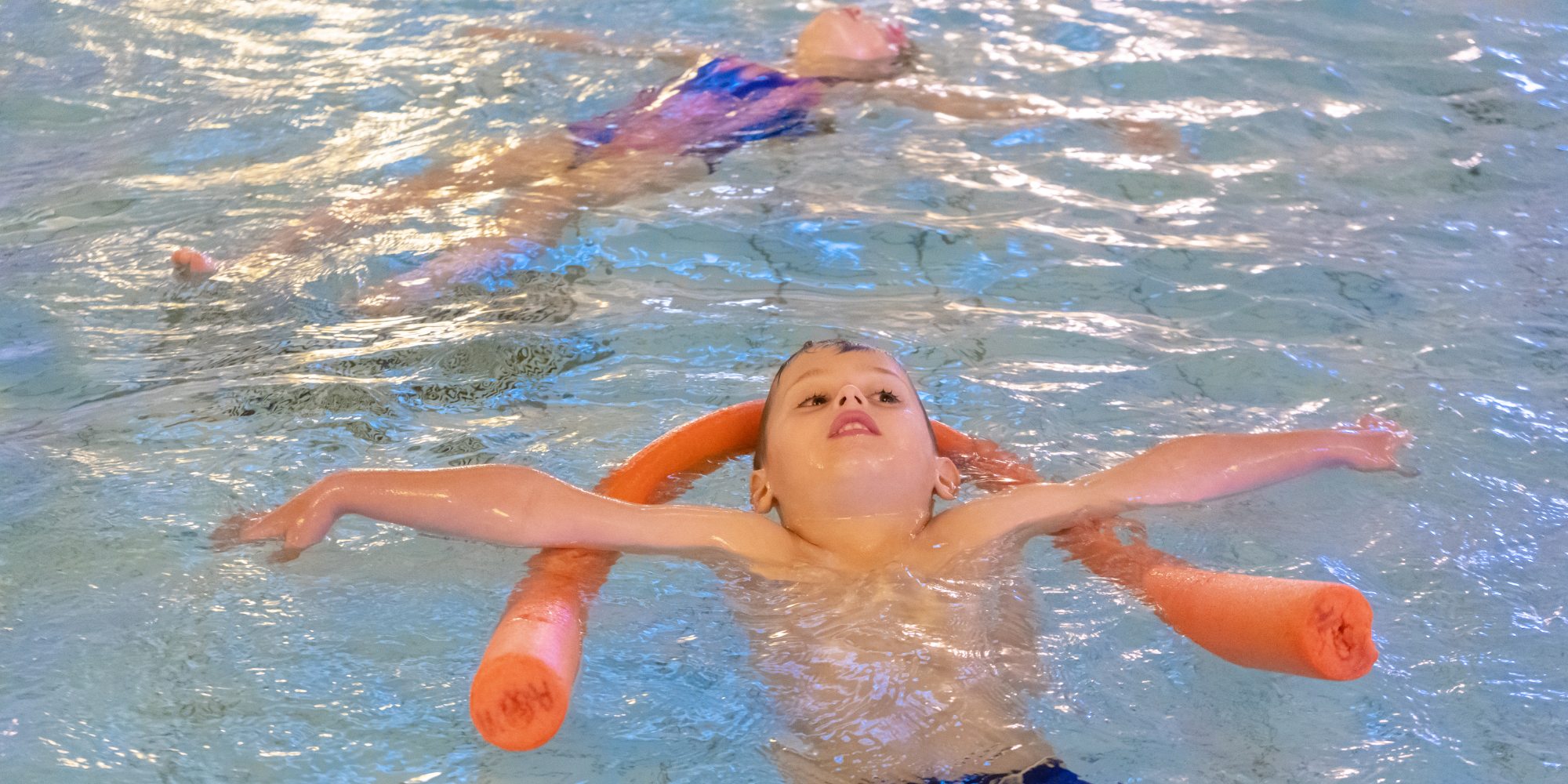 children in the pool with floats in a family swimming session