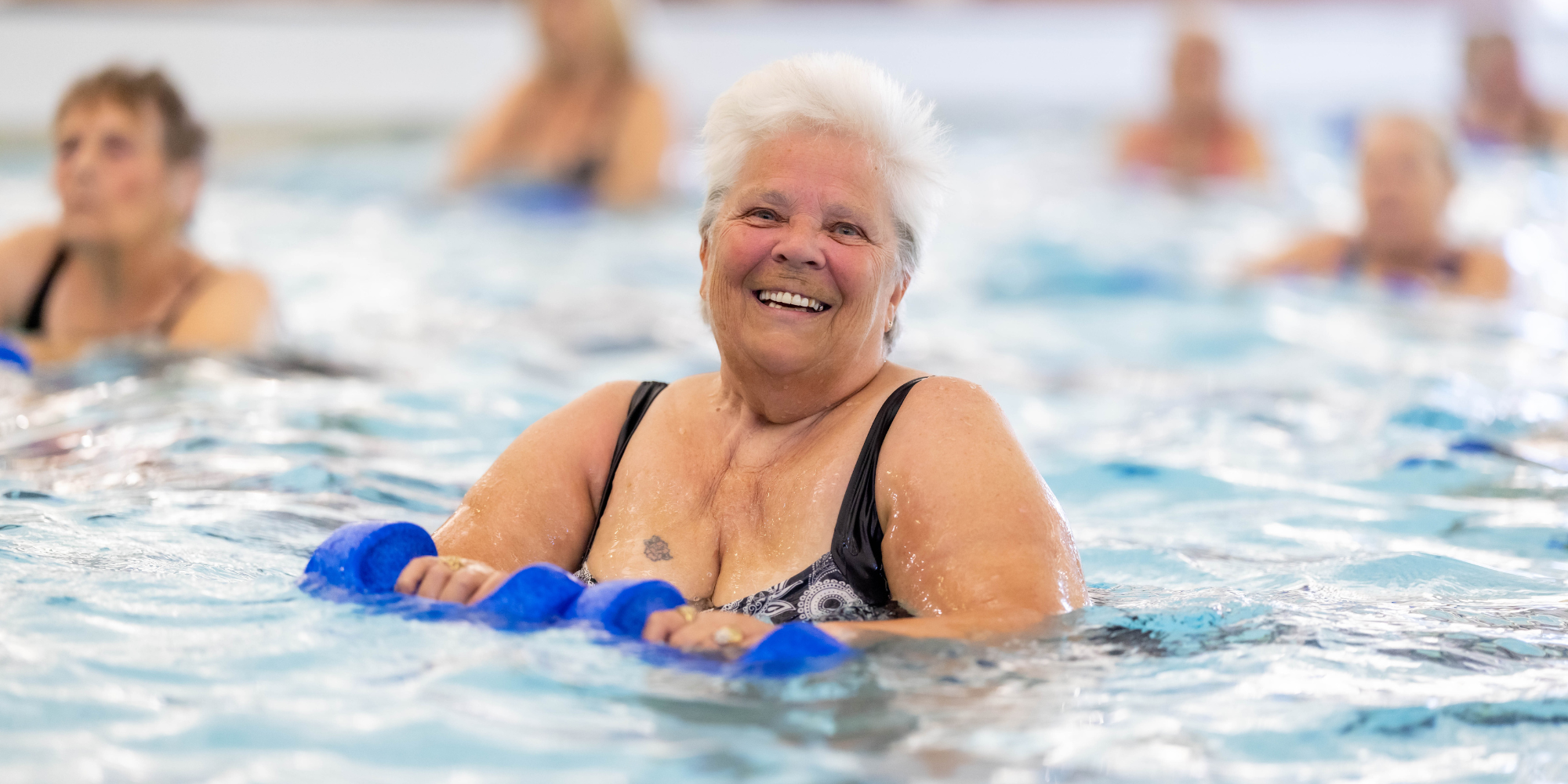 woman with dumbbell floats in a aqua aerobics session at palatine with other participants in the background