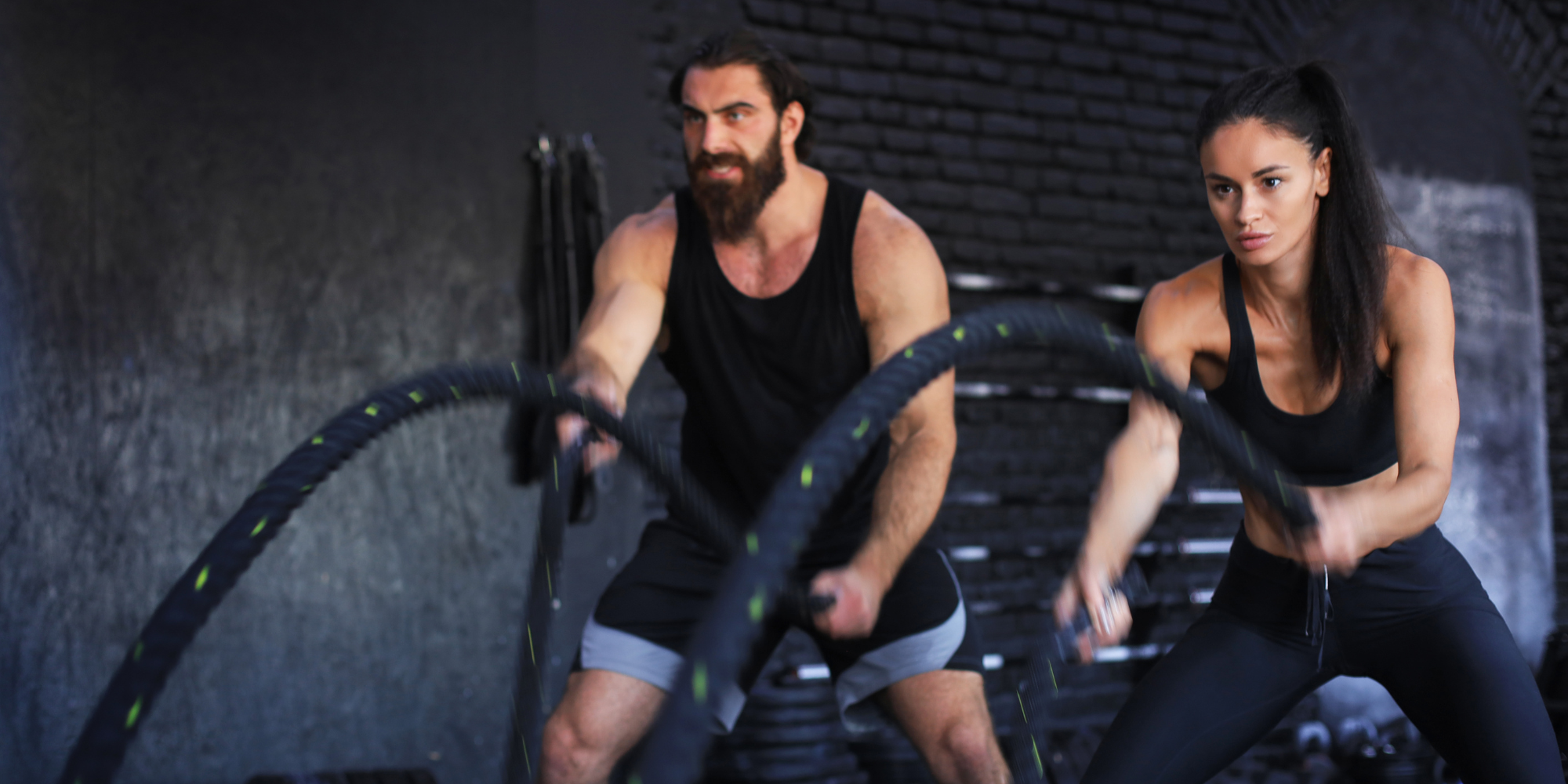 man and woman using battle ropes