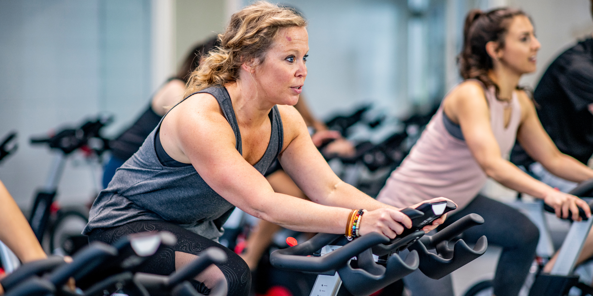 two women on indoor cycling bikes working out