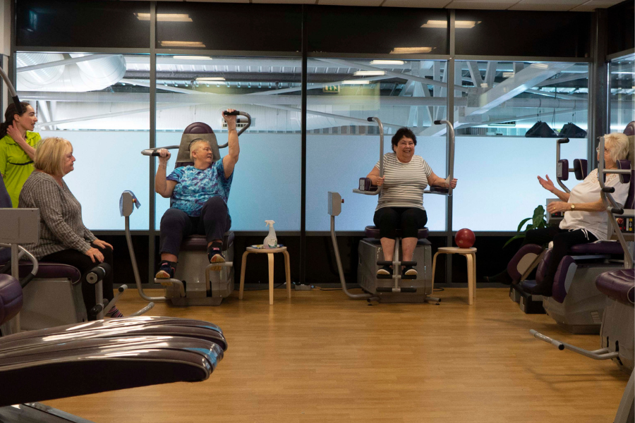 Four women and an instructor having a chat whilst exercising in the Feel Good Factory