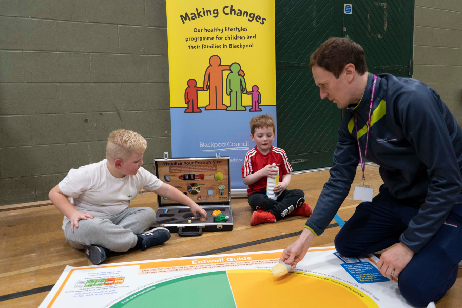 two children and an instructor playing with simulated foods, learning about healthy eating in a making changes session