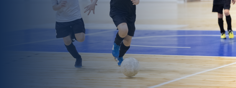 two people chasing the ball playing indoor football