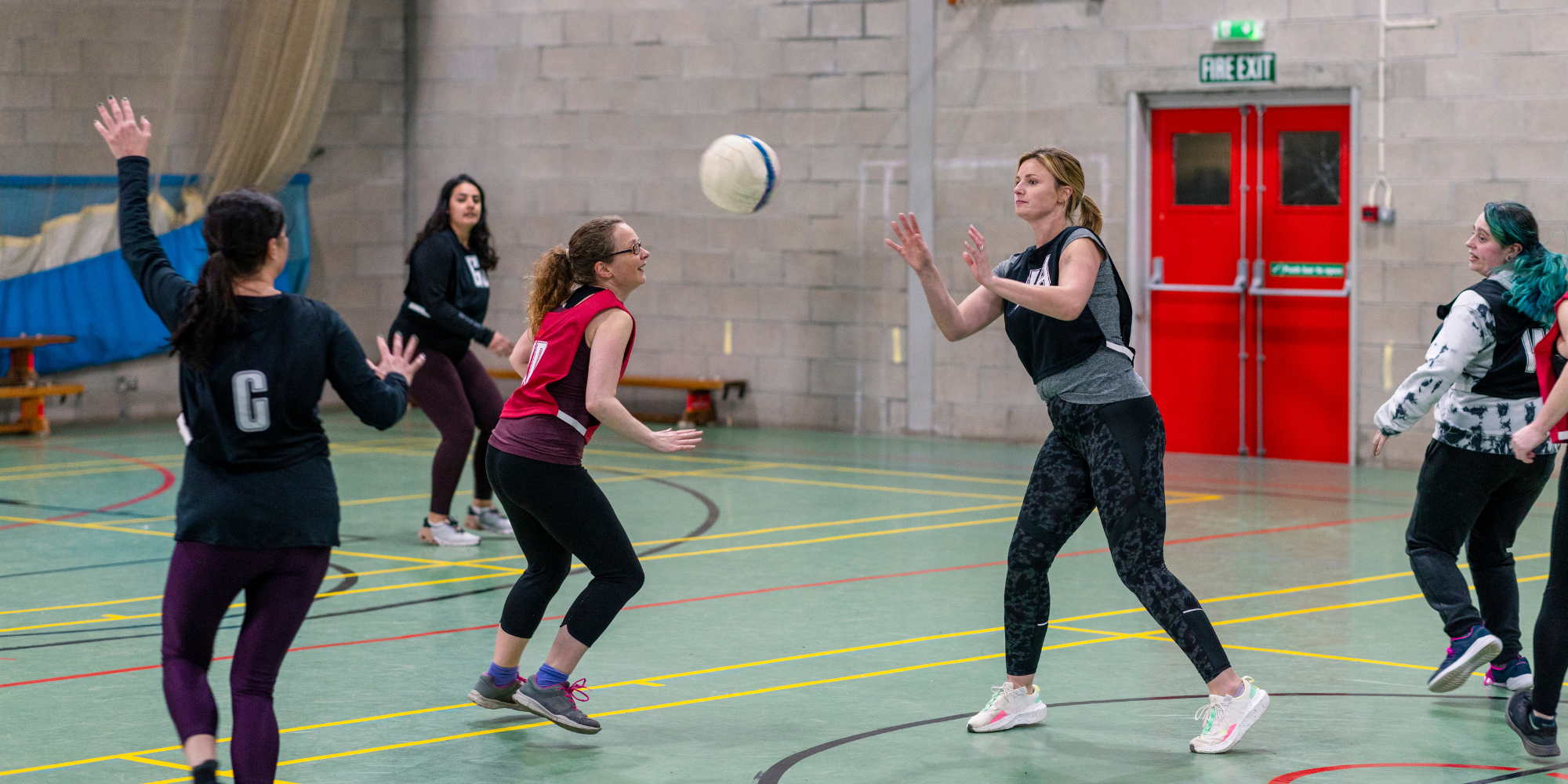 group of people playing netball in a sports hall