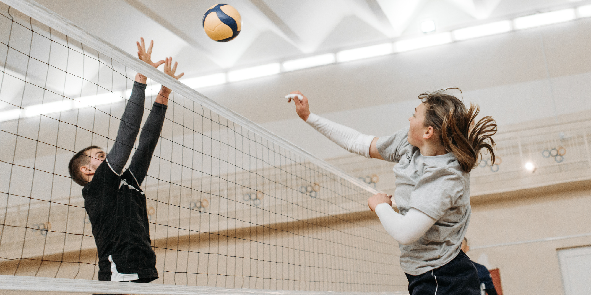 one man blocking a ball over the net playing volleyball