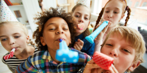 5 children blowing party horns celebrating a birthday