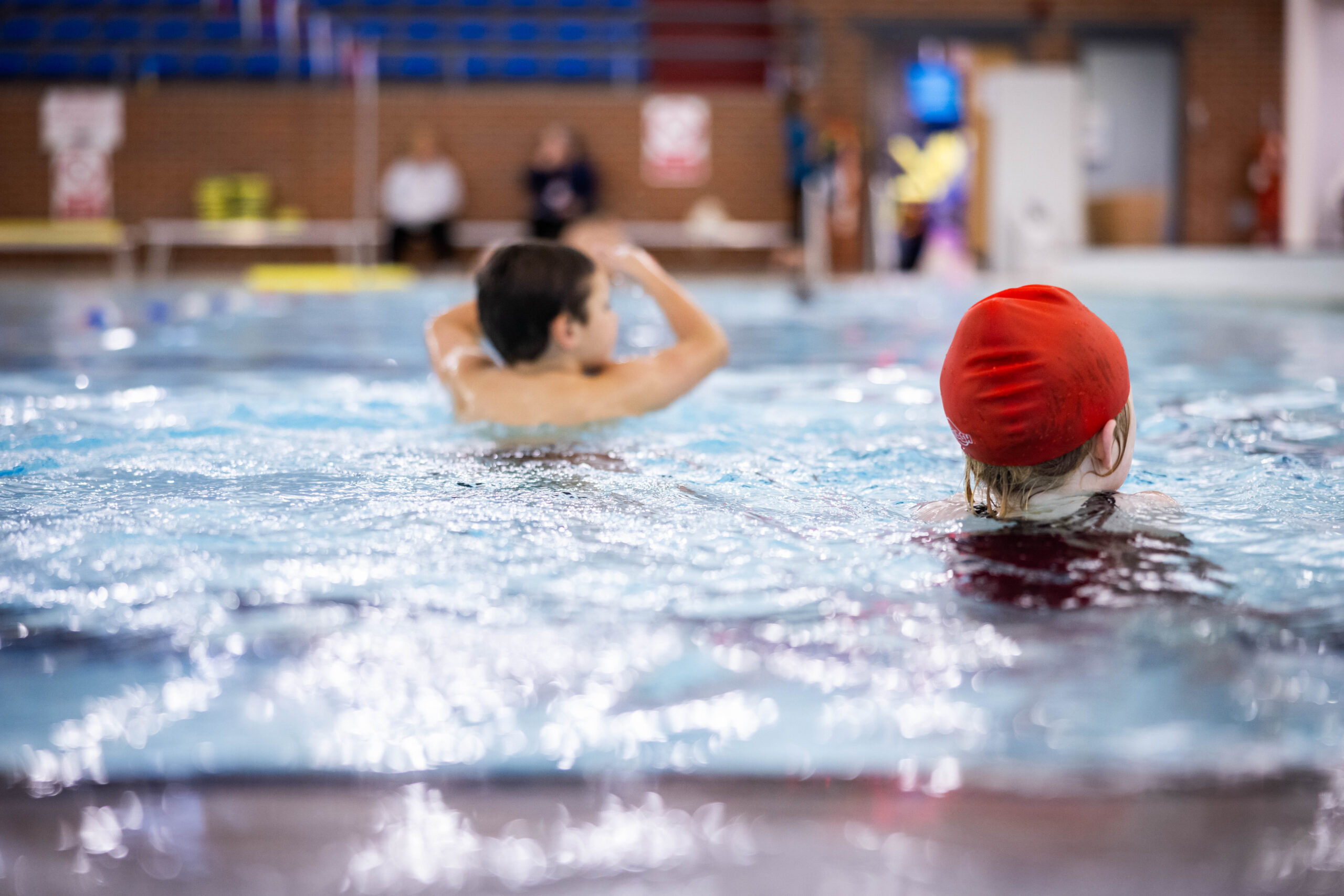 a young boy and girl walking across the swimming pool