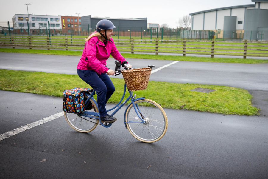 woman in a pink jacket riding a bike on the track at palatine leisure centre