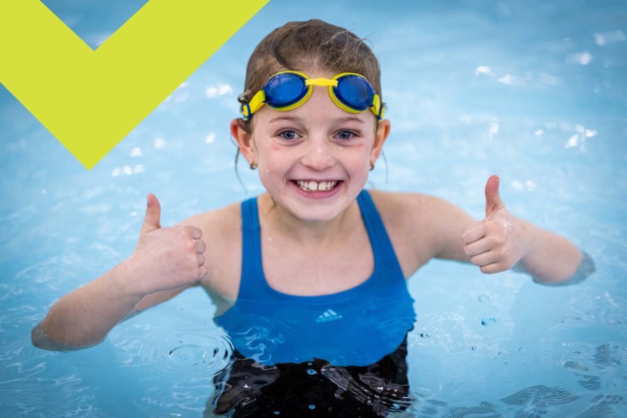 a girl in the swimming pool in a free swimming session giving a thumbs up