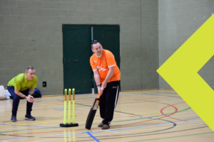 a man crouching behind cricket stumps with a man in front of the preparing to take a shot in a walking cricket